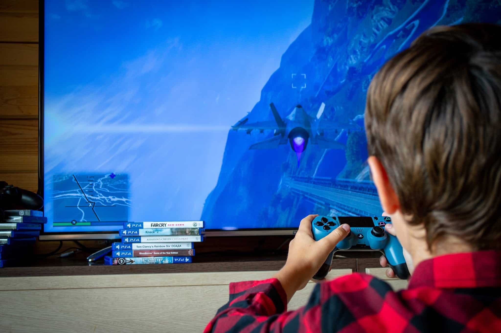 How to Connect PS4/PS5 to Computer Monitor - Back View of a Child Playing a Video Game