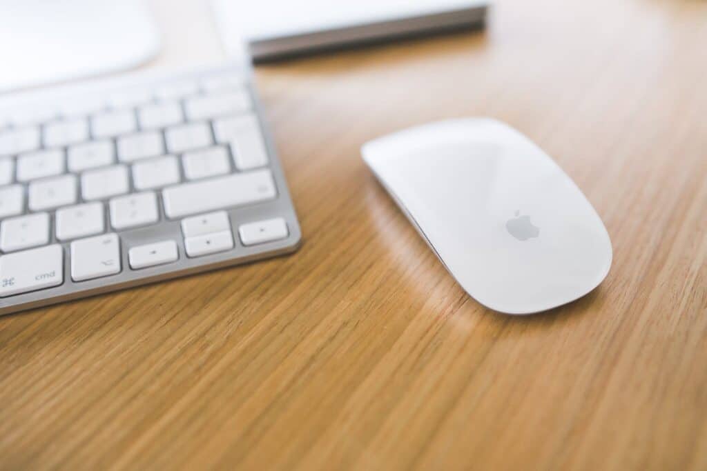 White Apple mouse and keyboard on a wooden desk